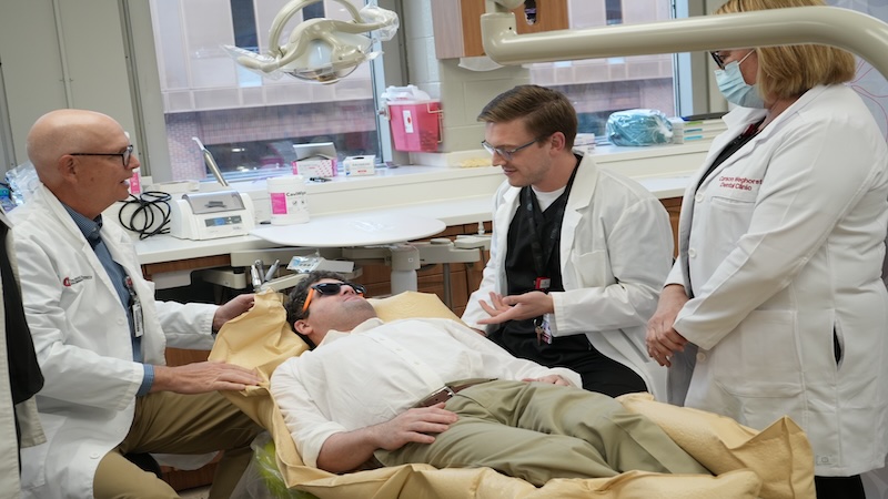 Three Ohio State dental staff talking to a patient laying in a dental chair