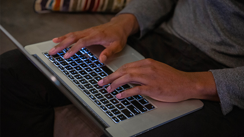 Hands of a man typing on a laptop keyboard